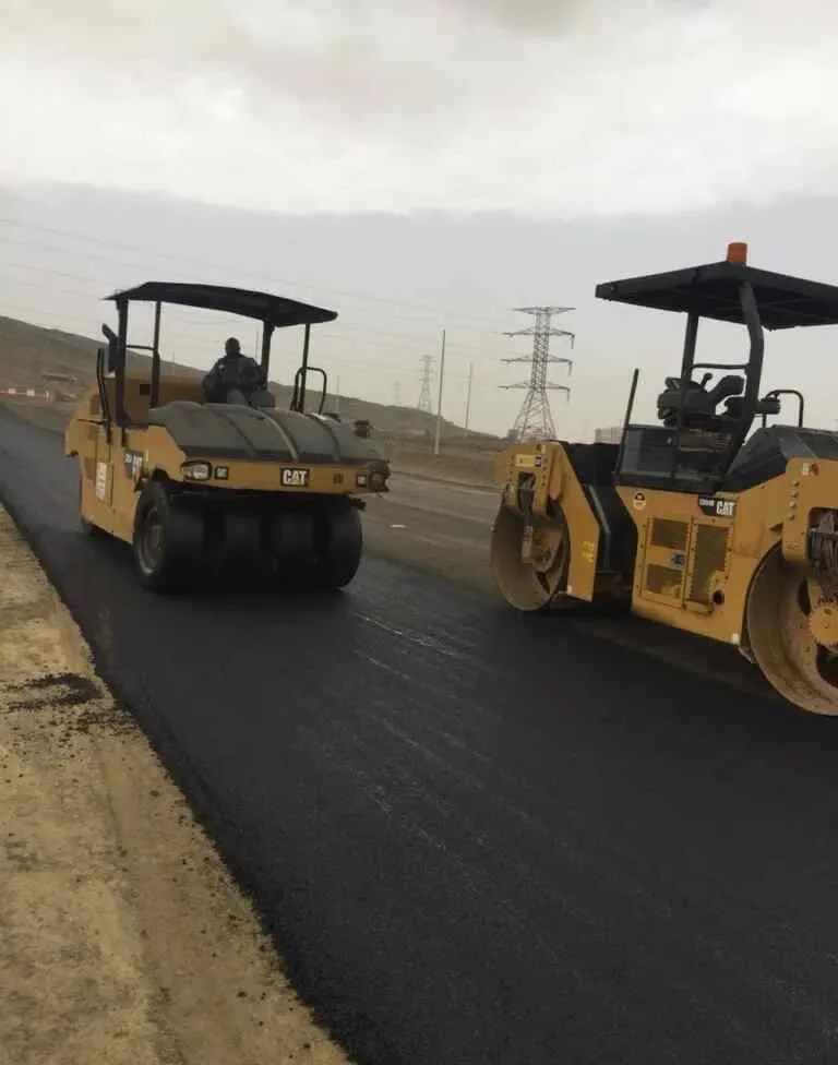 فريق سفلتة يفرش الأسفلت ويسويه في الموقع